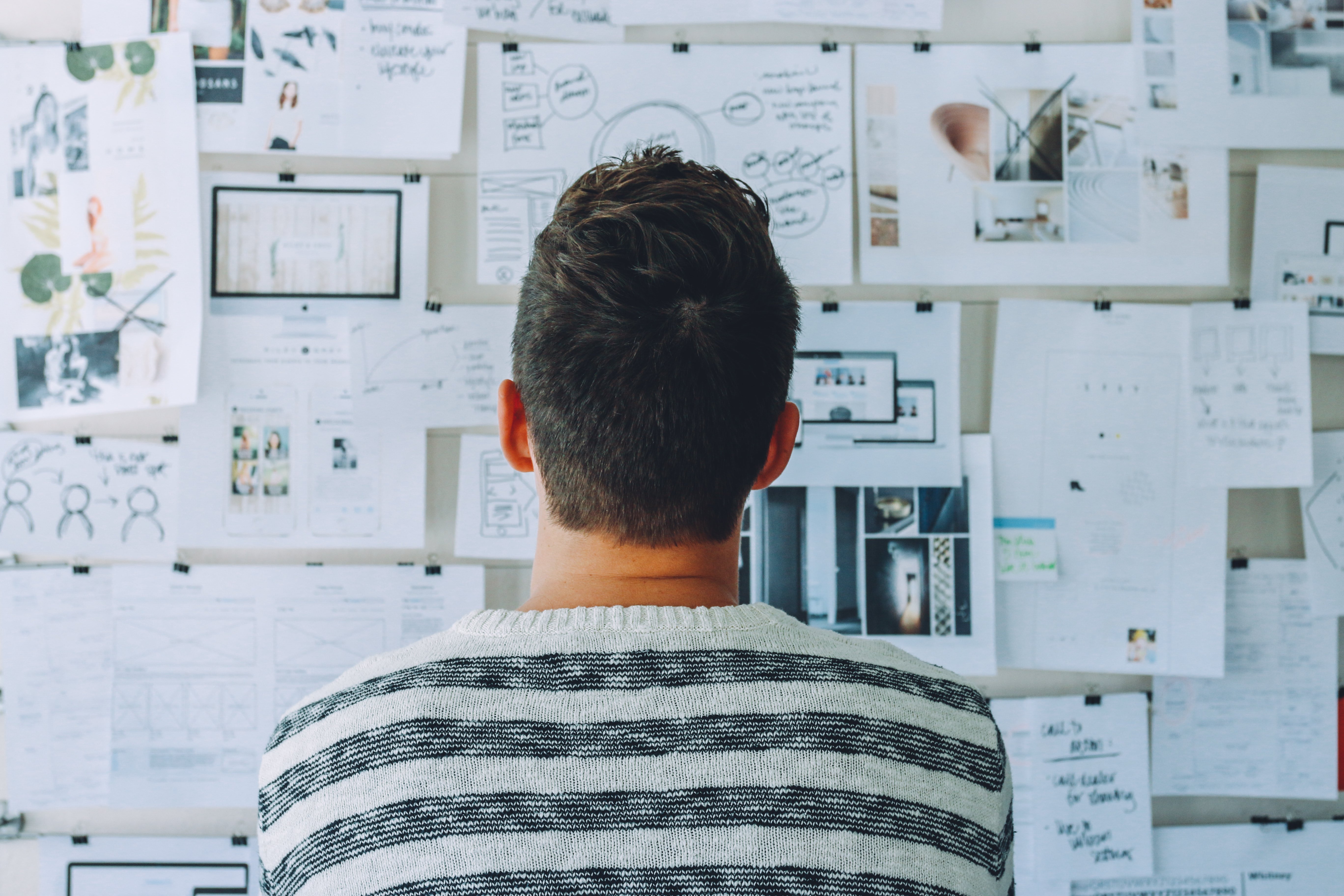 Canva - Man Wearing Black and White Stripe Shirt Looking at White Printer Papers on the Wall