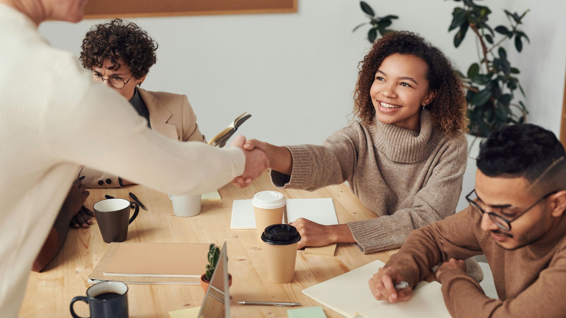 Session d'onboarding avec un groupe d'employés assis à une table dont une nouvelle recrue serre la main d'une employée