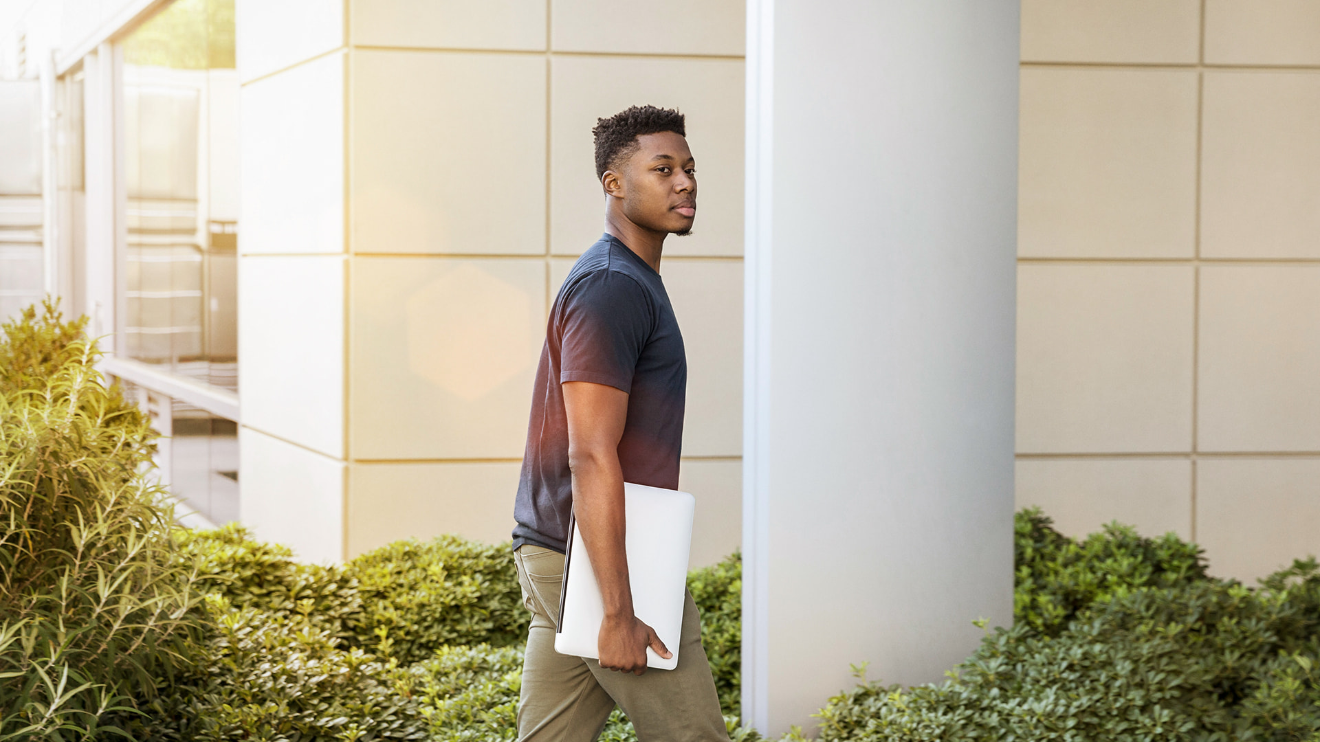 Jeune étudiant avec un ordinateur portable sous le bras en route pour le bureau pour son stage à l'étranger