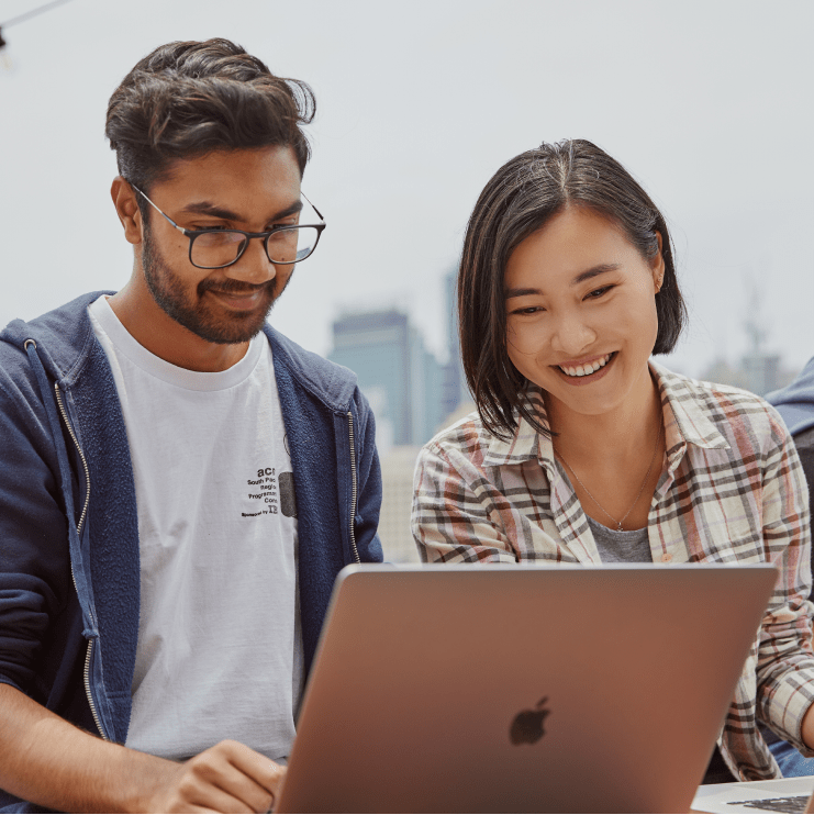 A person using a laptop with another person watching