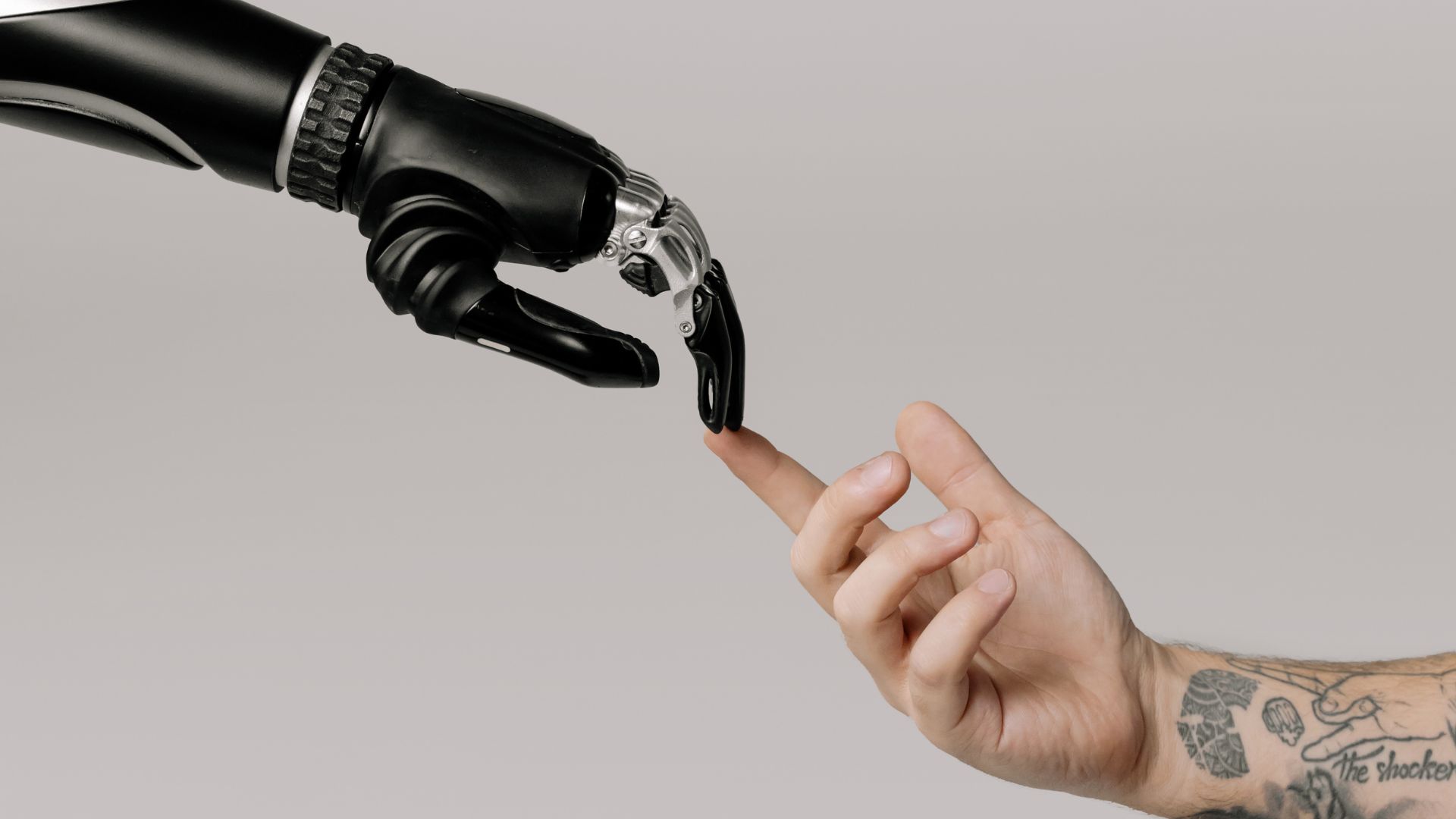 Main de robot touchant une main humaine avec des tatouages sur le bras